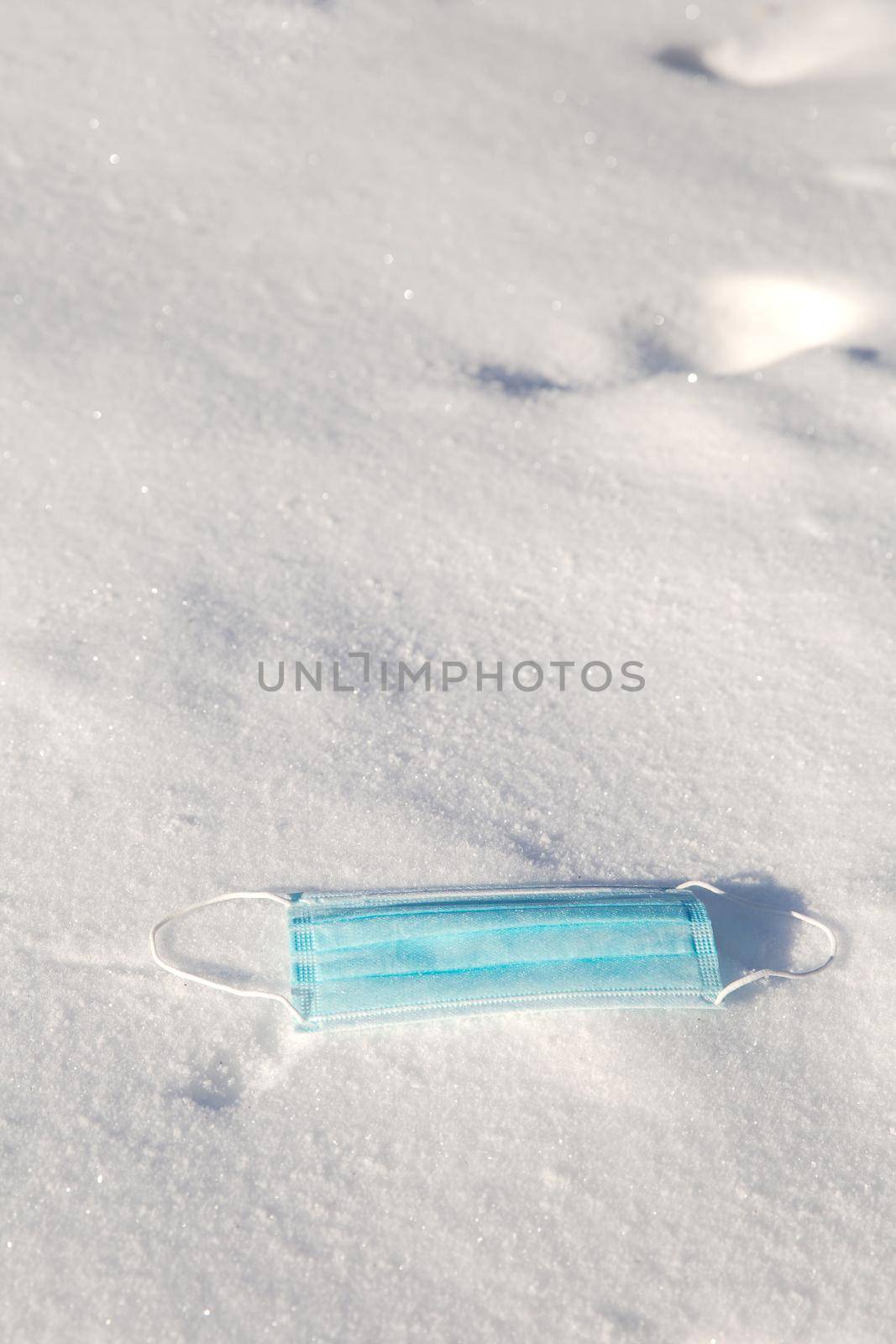 Protective blue medical mask for virus lies in the snow, Covid-19, pandemic,winter,virus,health concept, copy space background space for text