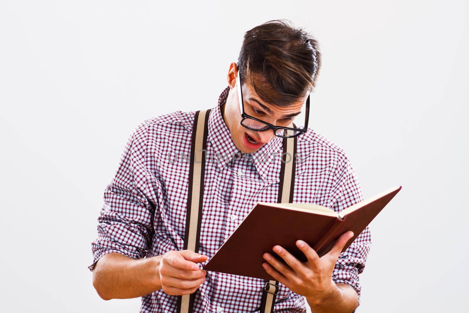 Portrait of surprised nerdy man reading book.