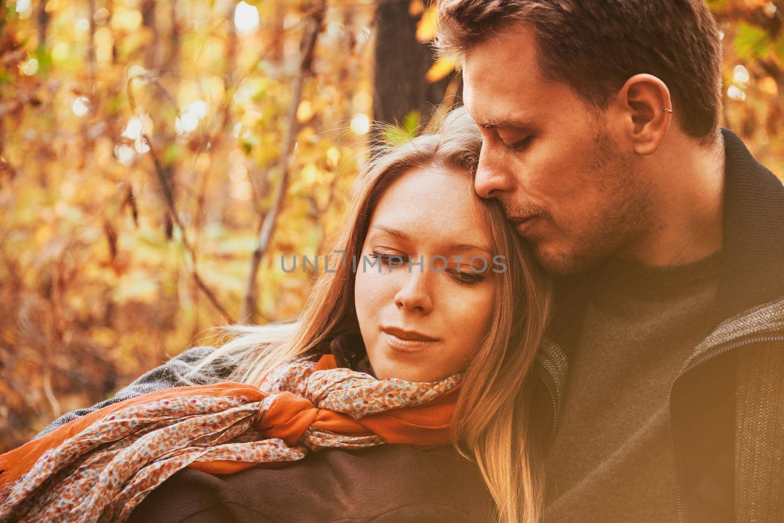 Loving couple rests in autumn park. Image with sunlight effect.