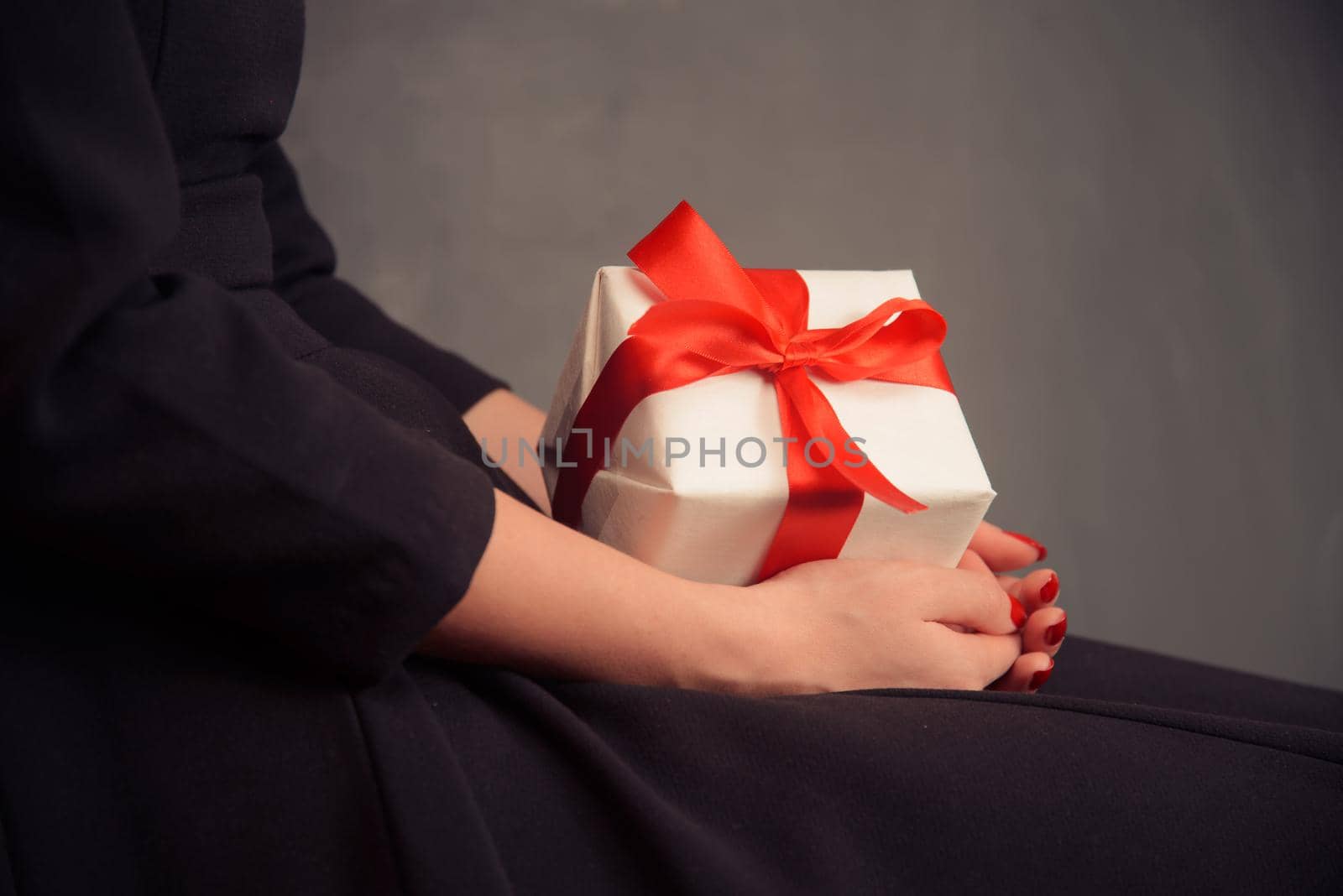 Unrecognizable woman in dress is holding a present, side view