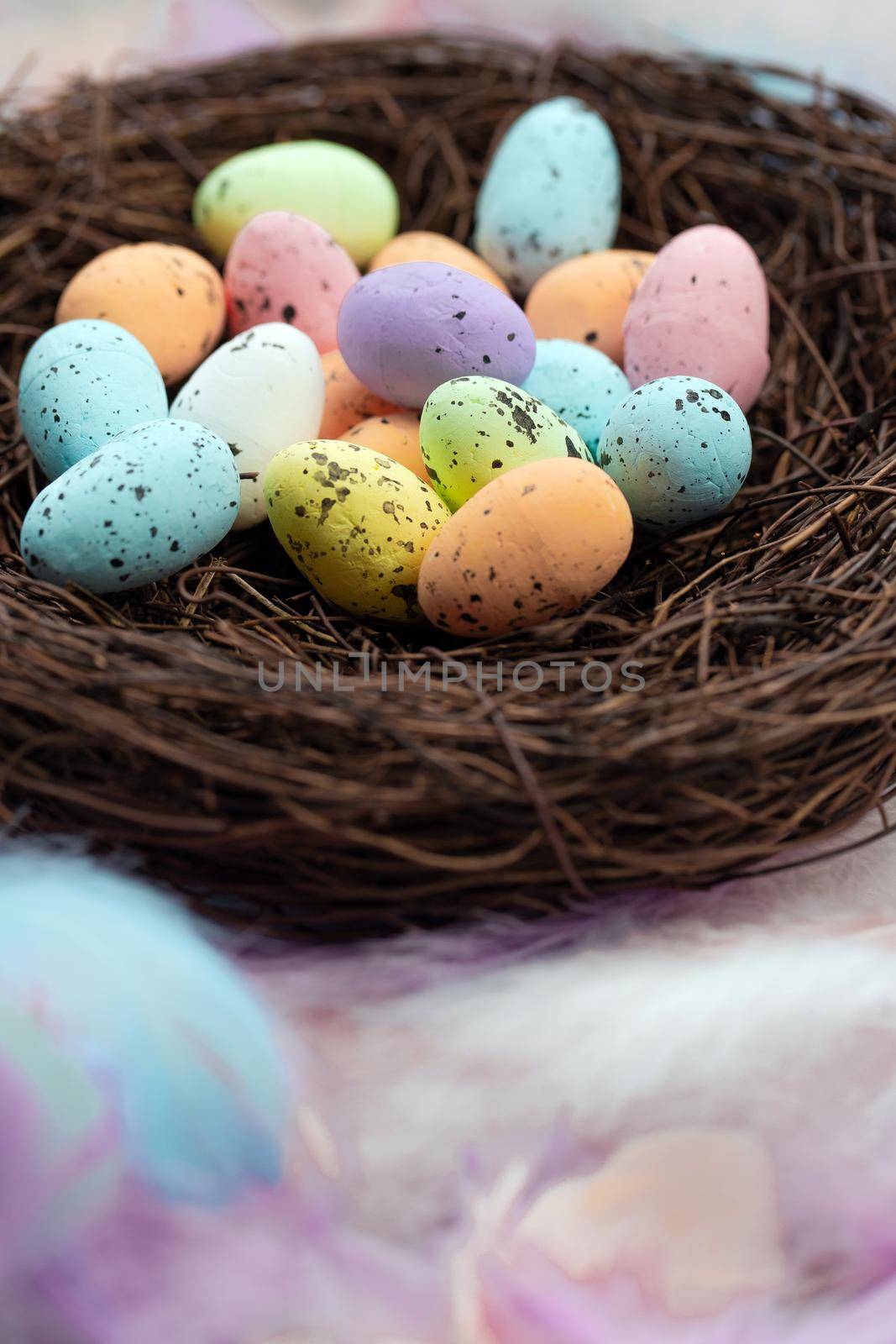 Colorful pastel colored easter eggs in bird's nest top view with bright feasthers top view, April, Easter Holliday, Religion and spring concept background close up