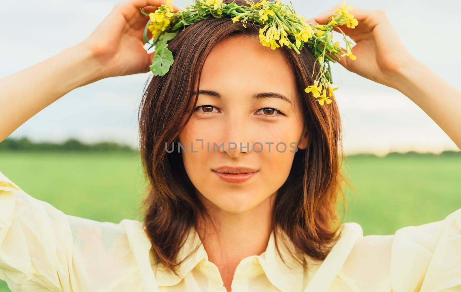 Portrait of attractive brunette young woman with wreath of flowers in summer