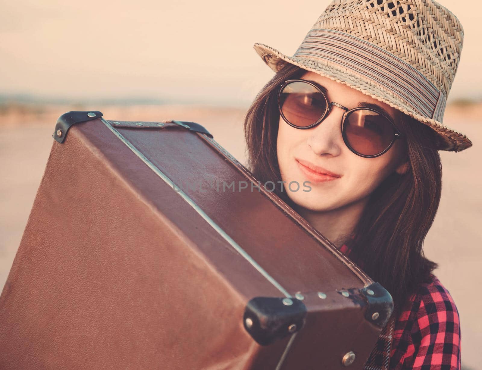 Smiling hipster woman traveler hugging a suitcase. Image with vintage filter, low contrast effect.