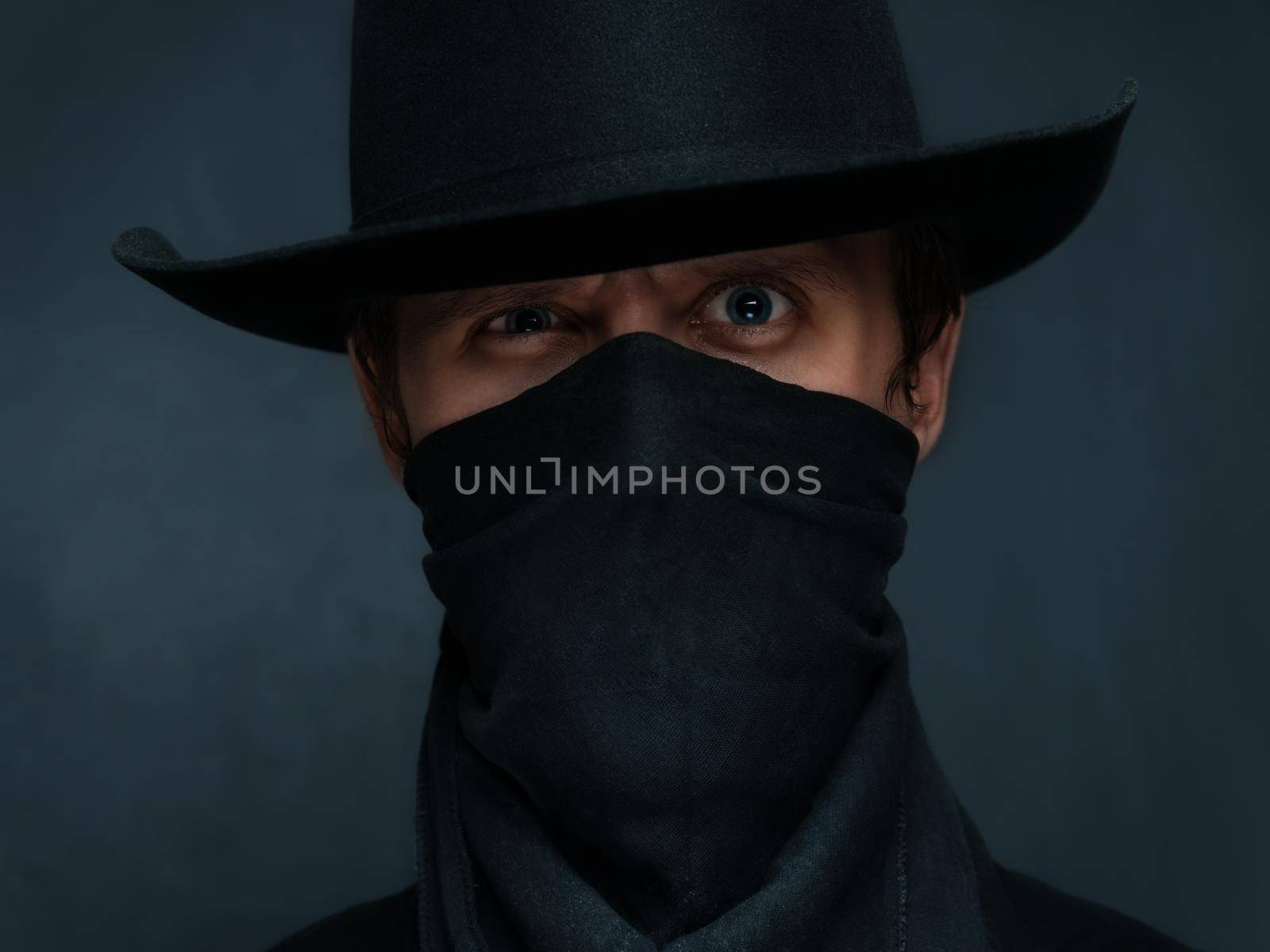 Man cowboy is surprised with a scarf on his face and in a black hat