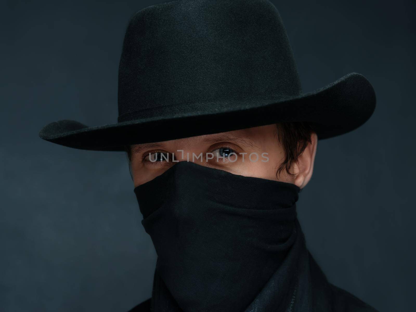 Portrait of a man cowboy with a scarf on his face and in a black hat