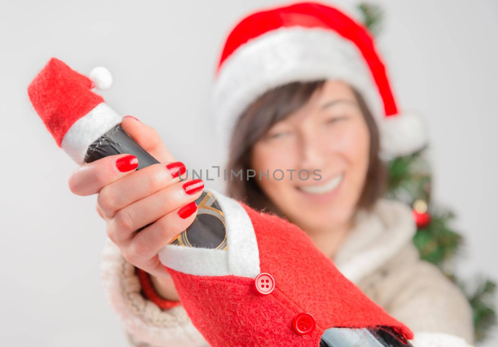 Woman in santa hat giving a bottle of champagne