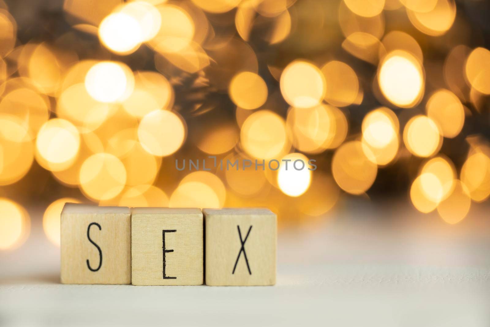 Three wooden cubes with letters SEX on them with colorful gold shiny bokeh background. by Annebel146