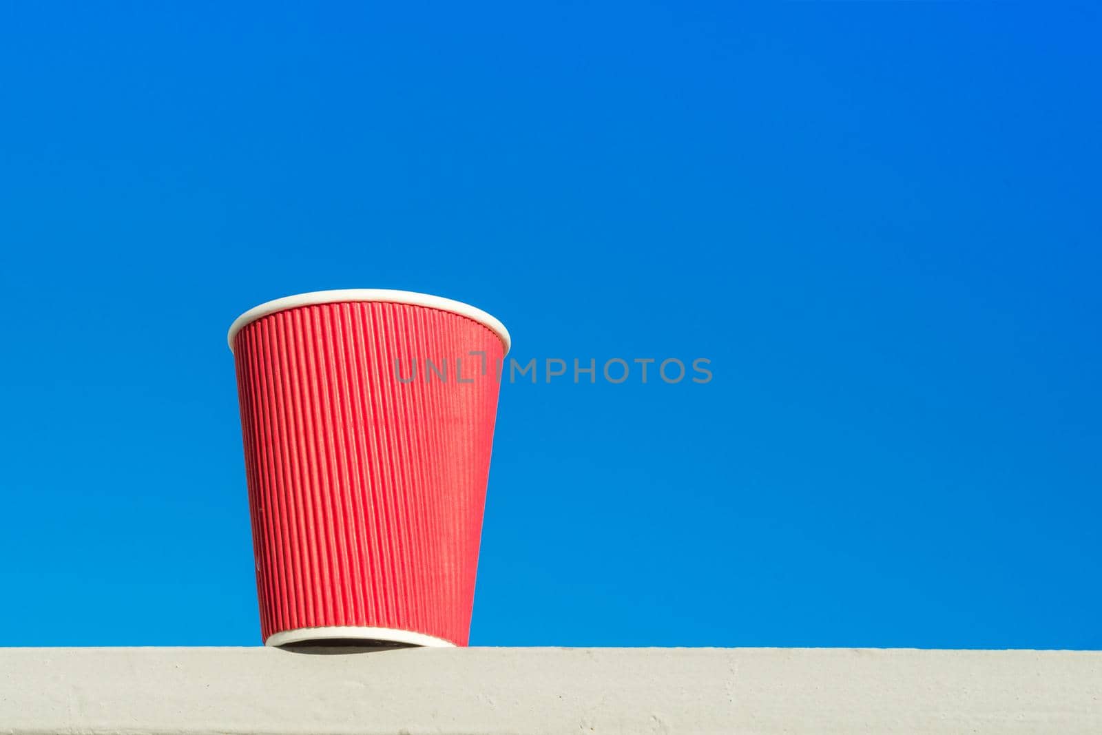 Red paper cup. Blue sky background, copy space