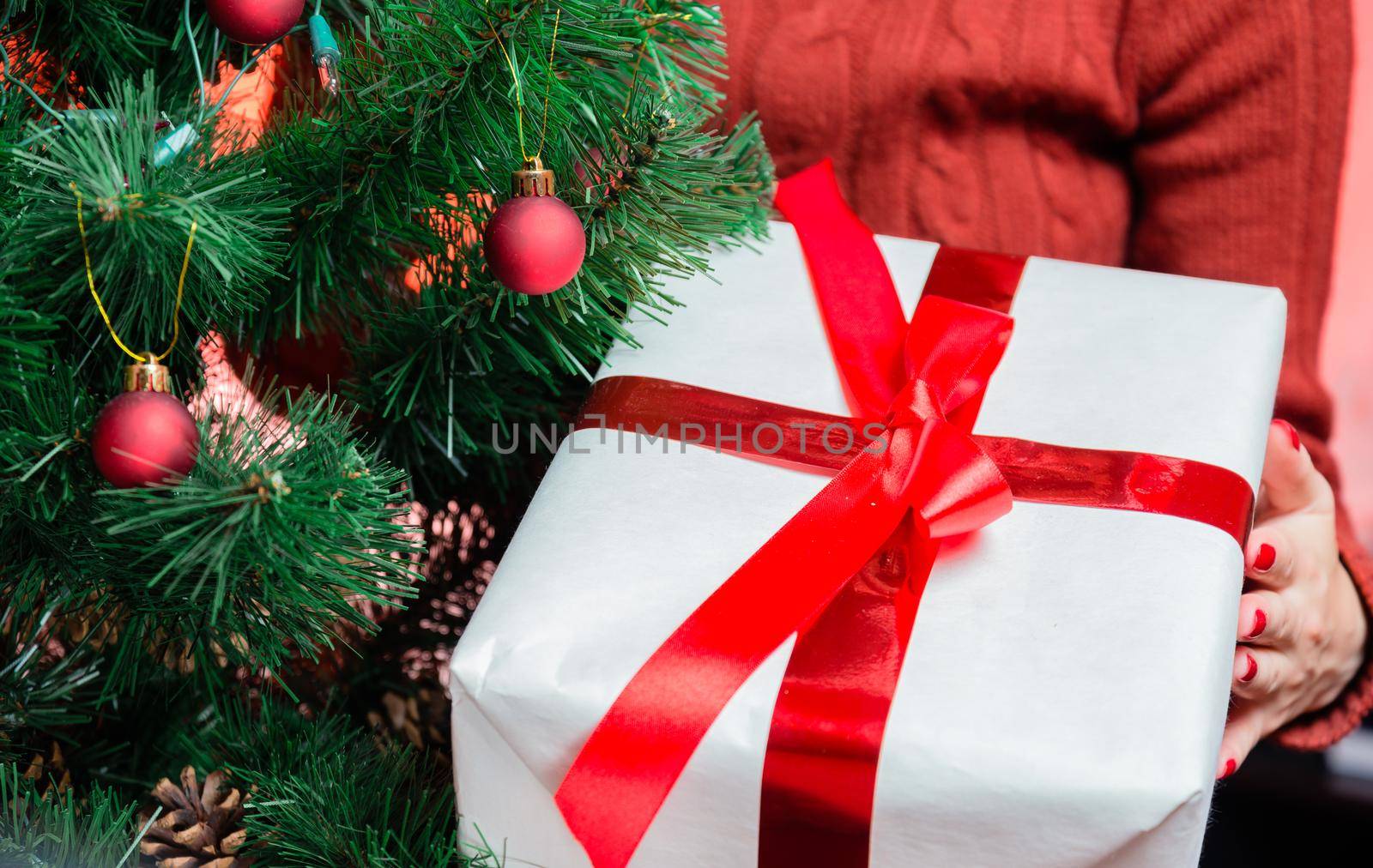 Unrecognizable woman is holding gift box near christmas tree
