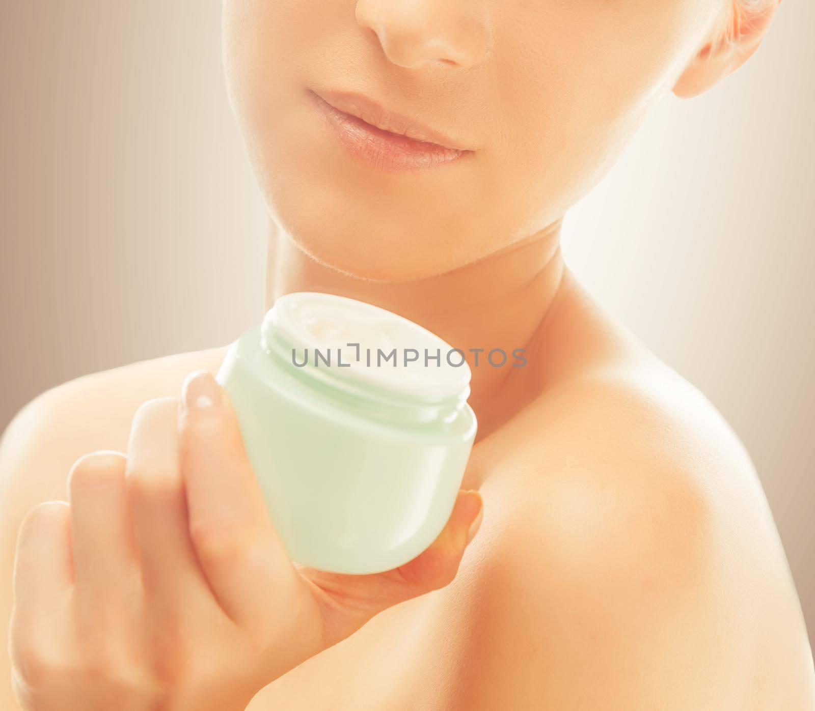 Unrecognizable woman holds a jar of cream near the face