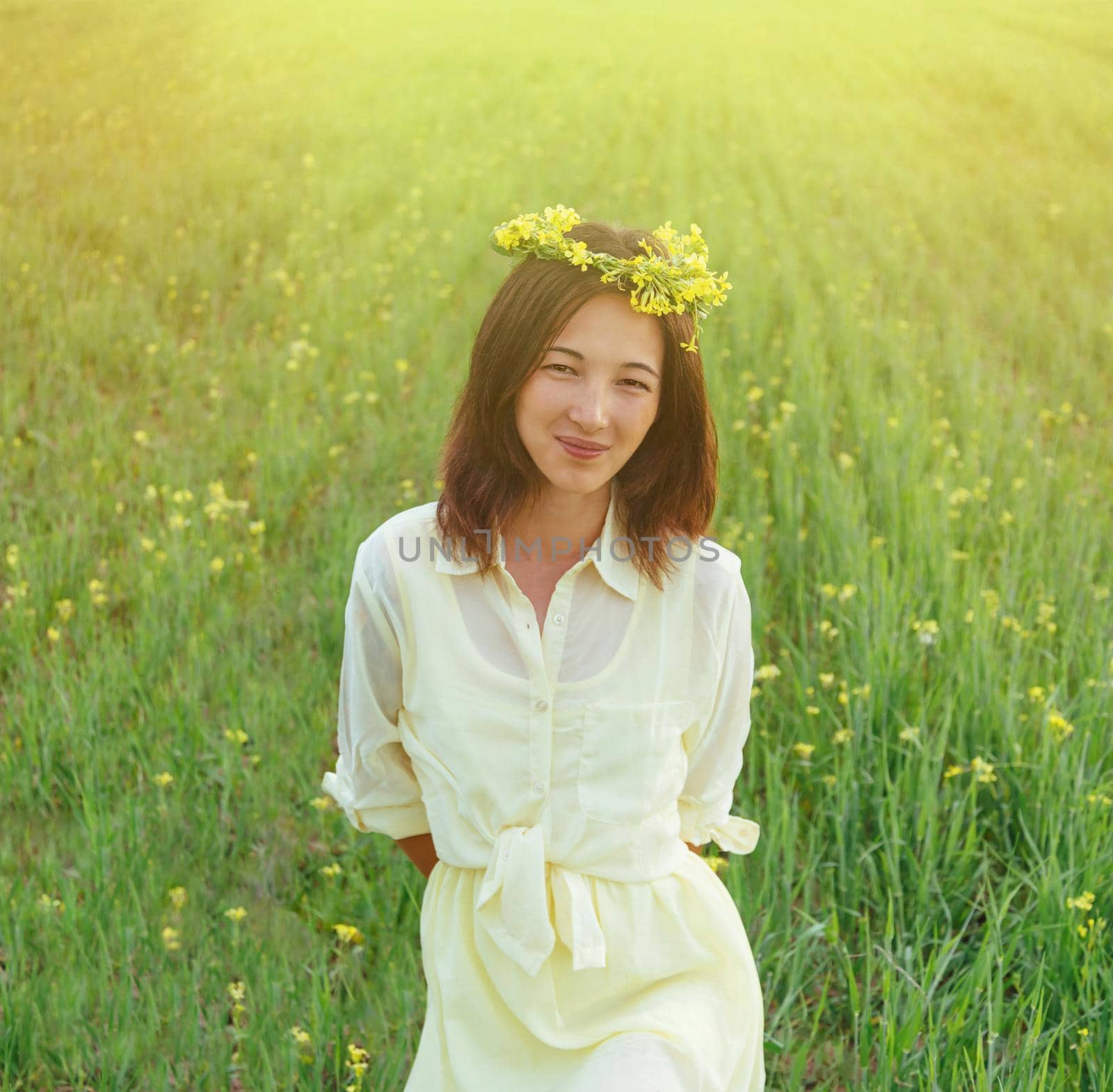 Smiling beautiful brunette young woman with wreath of flowers in summer outdoor
