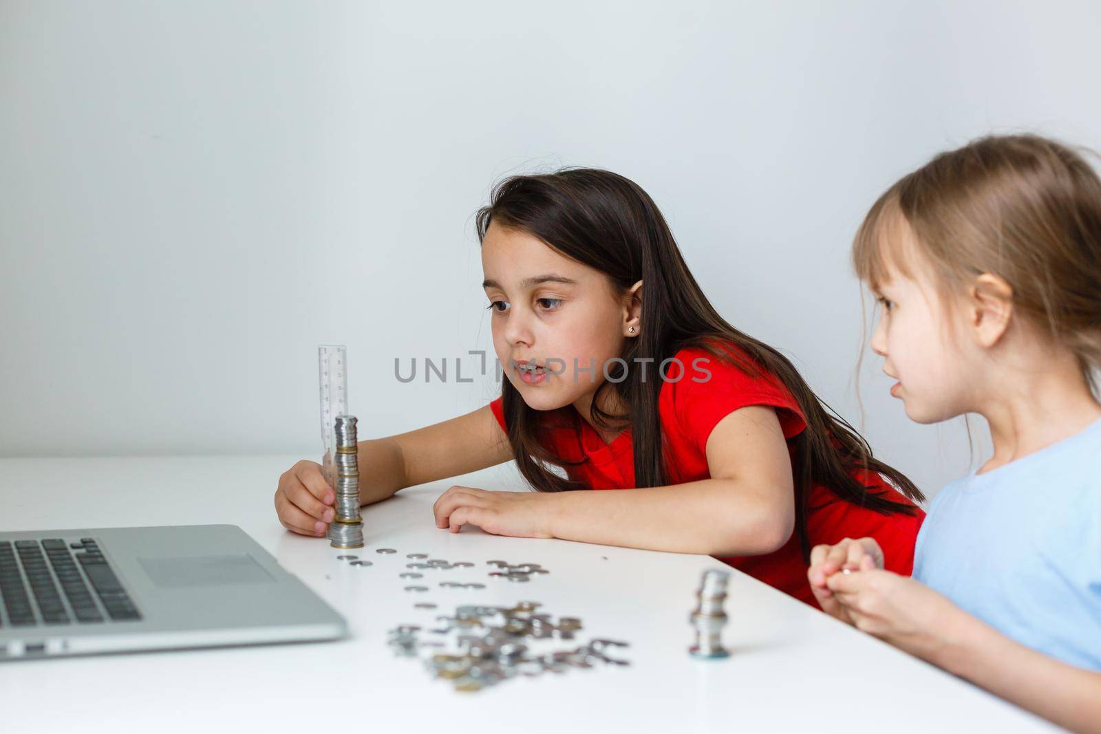 portrait of little girls sitting at table and calculating money