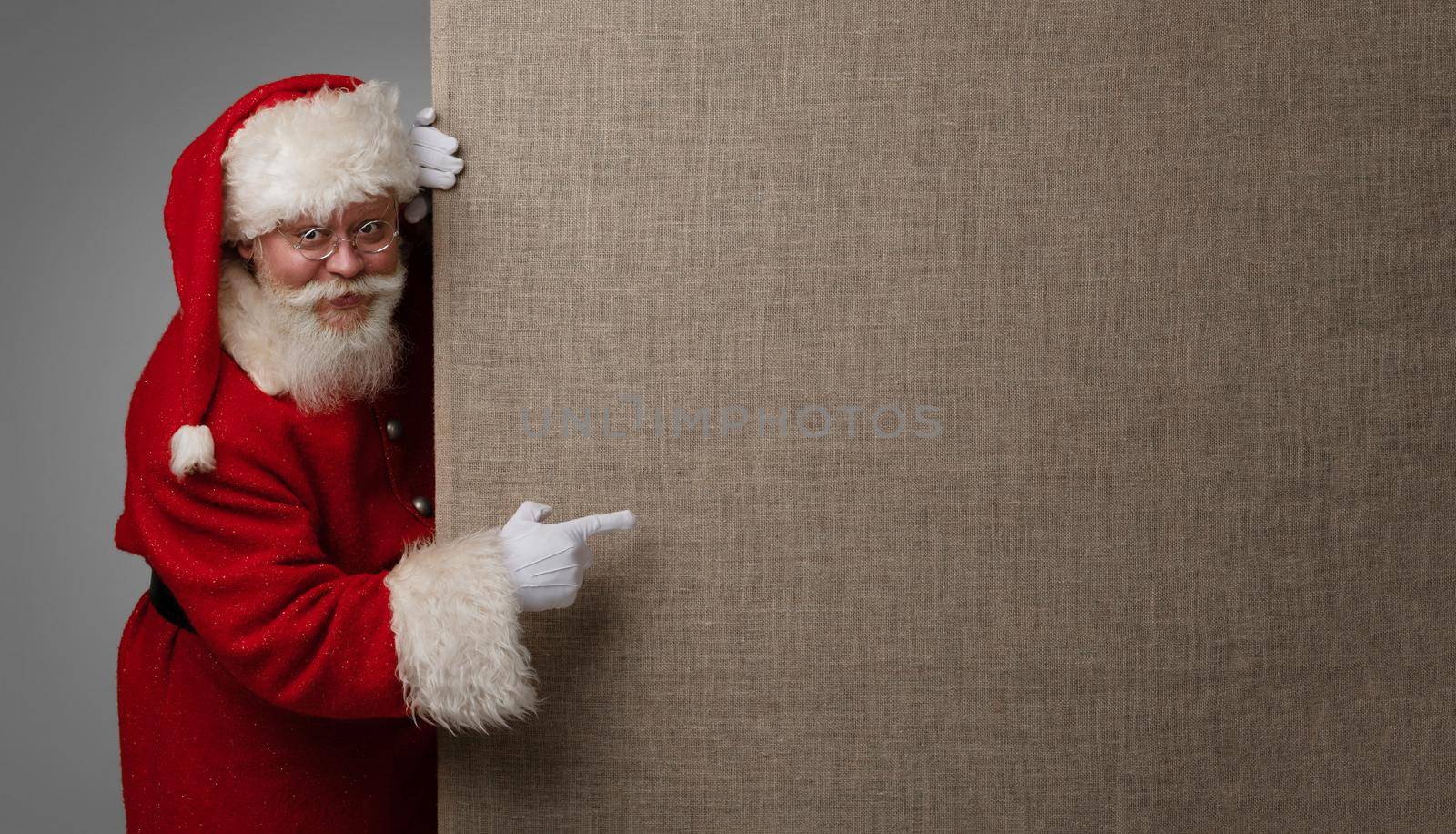 Santa Claus pointing at fabric billboard with copy space for text