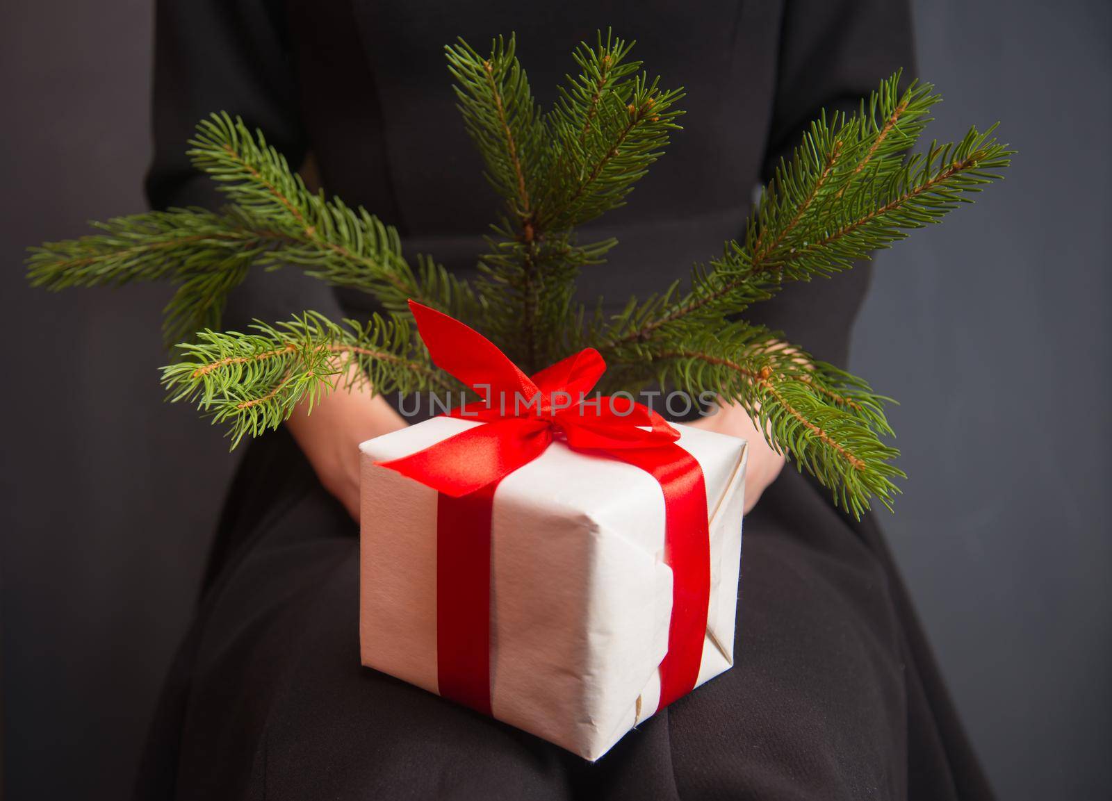 Woman is holding a white gift box and branch fir-tree
