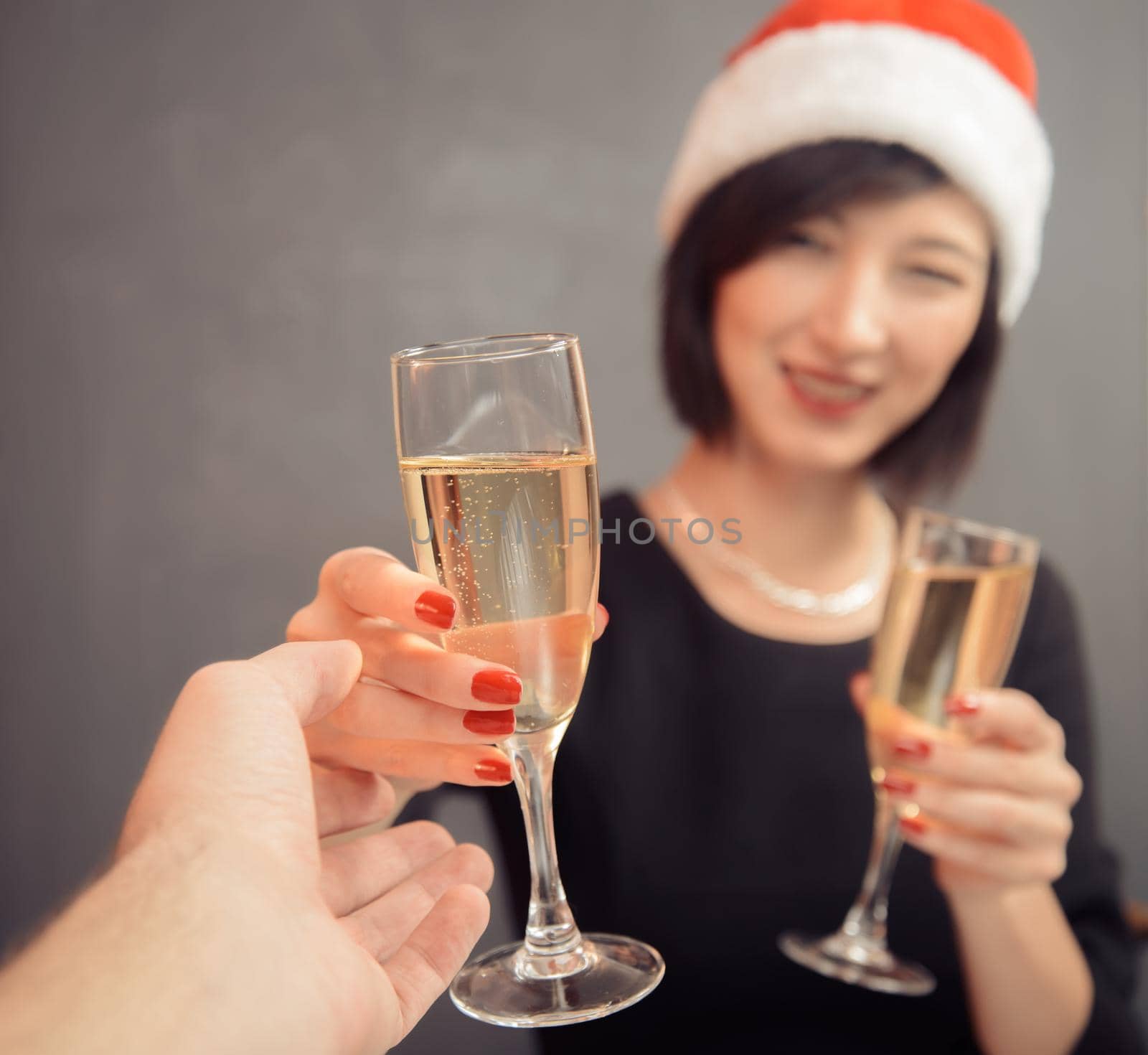 Young woman in santa hat is giving glass with champagne