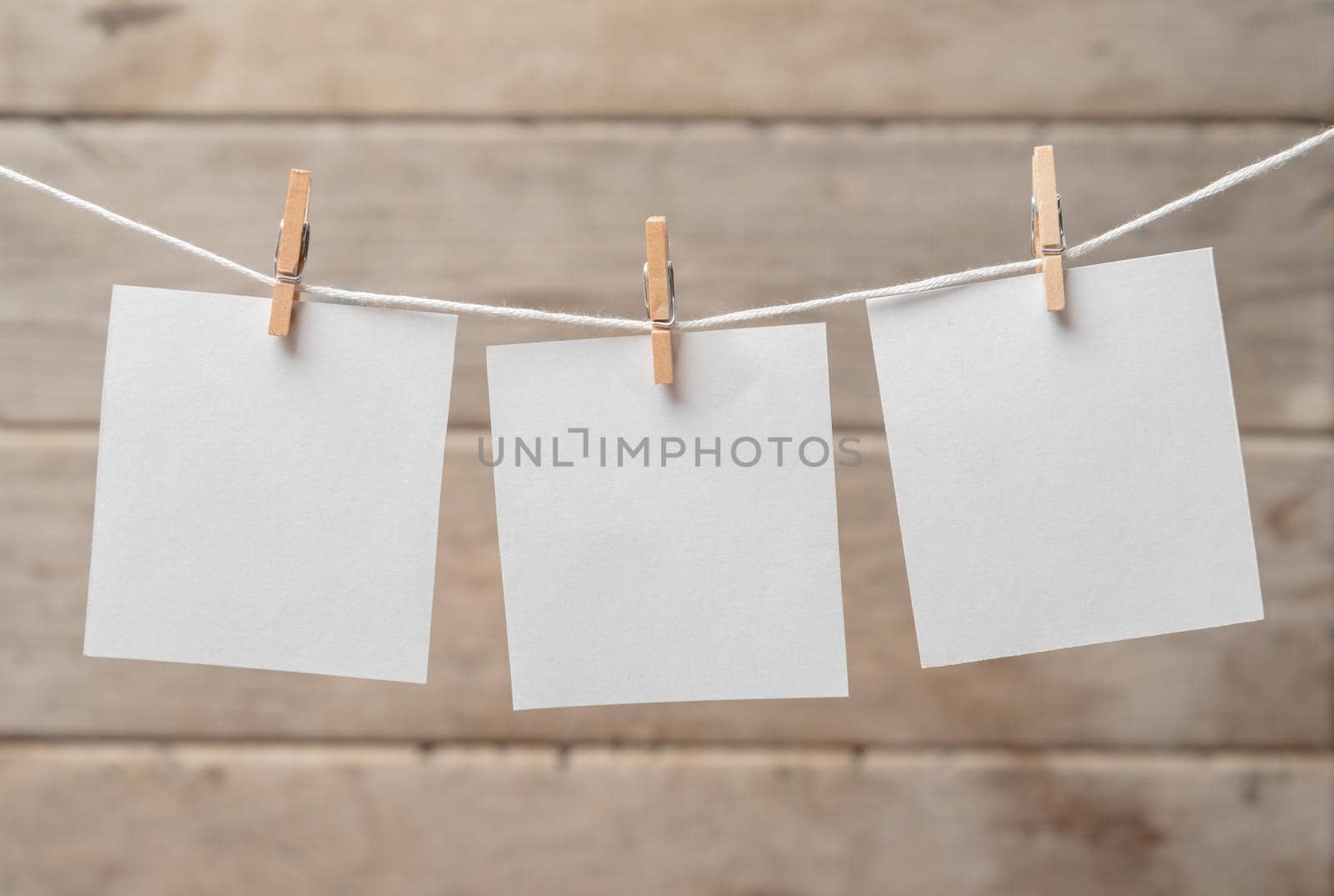 Sheets of paper on a clothespins on a wooden background, space for text