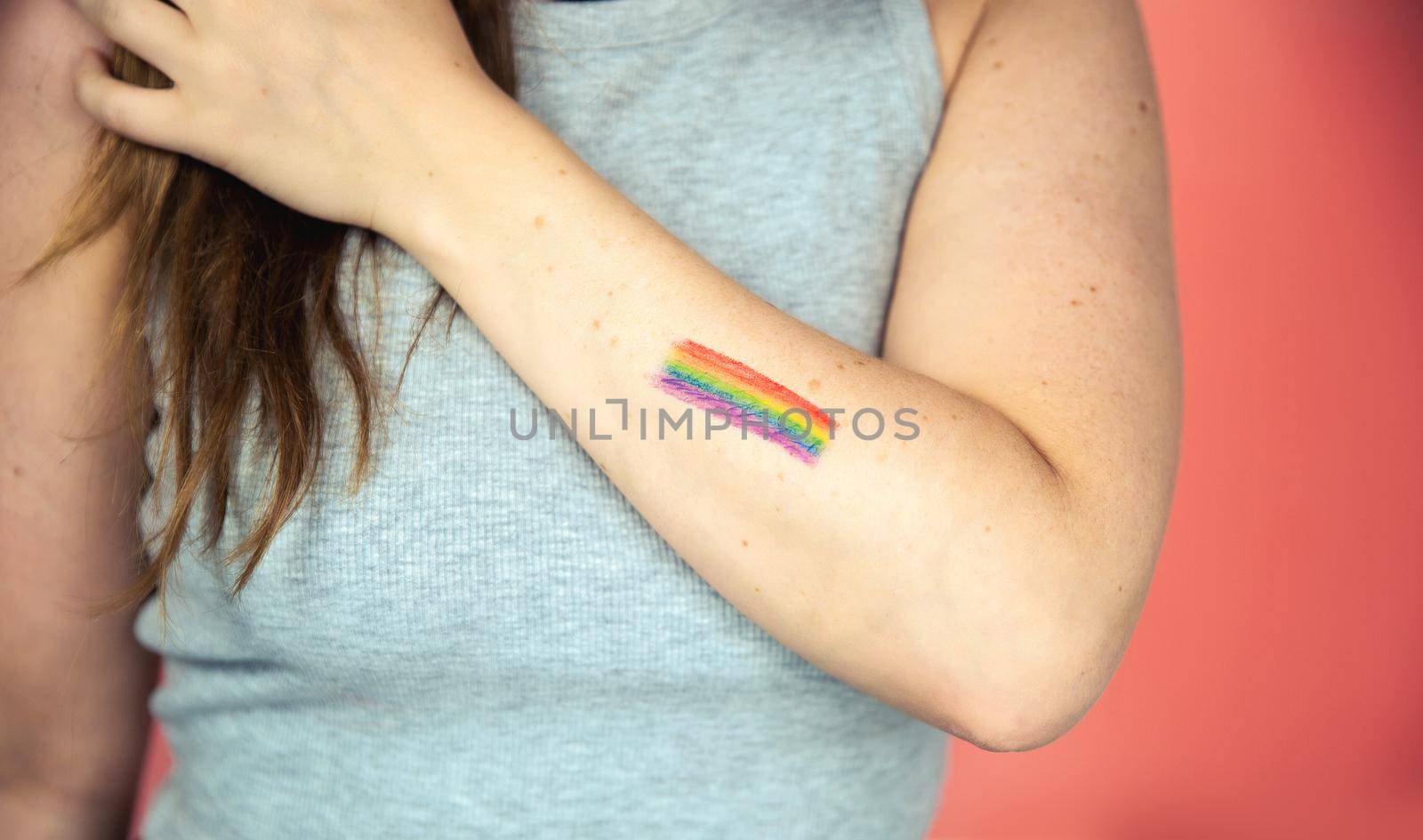 Portrait of a young woman with rainbow Flag on cheek and body, the LGBT community on a colorful pink background freedom, LGBTQ concept beauty