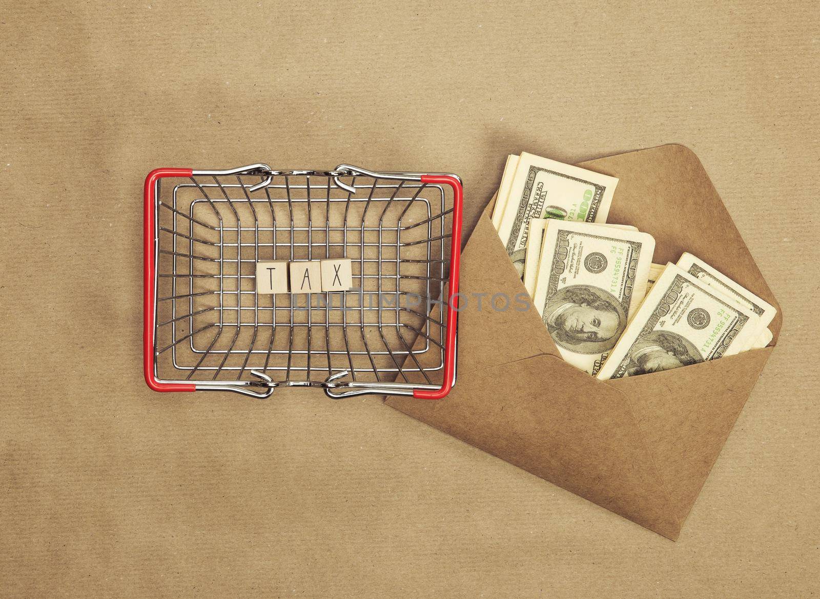 Personal tax income concept, cube wooden block with word TAX with envelope with dollars, business and financial concept copy space top view craft paper