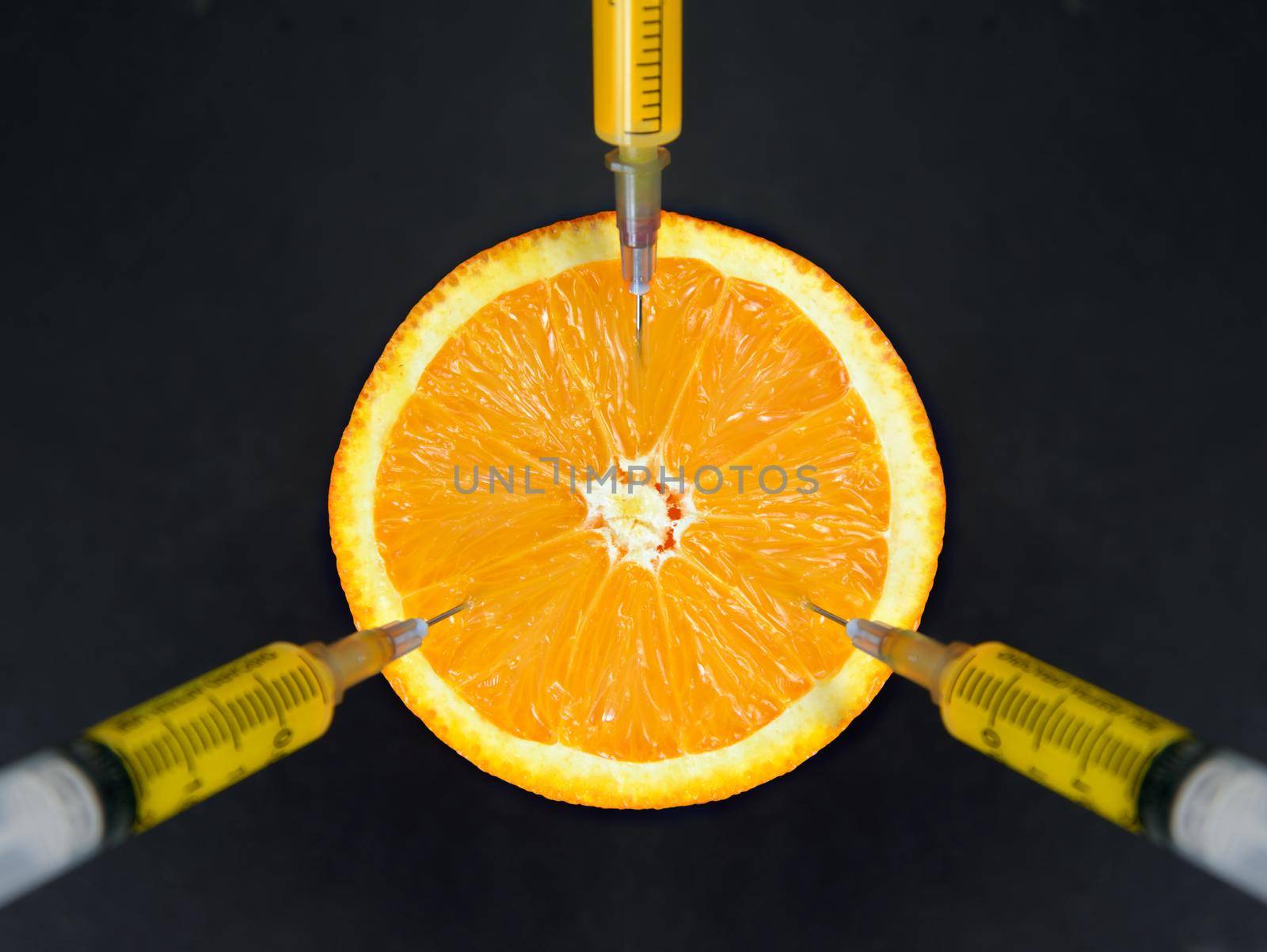 Syringes pumped out vitamins from an orange, top view
