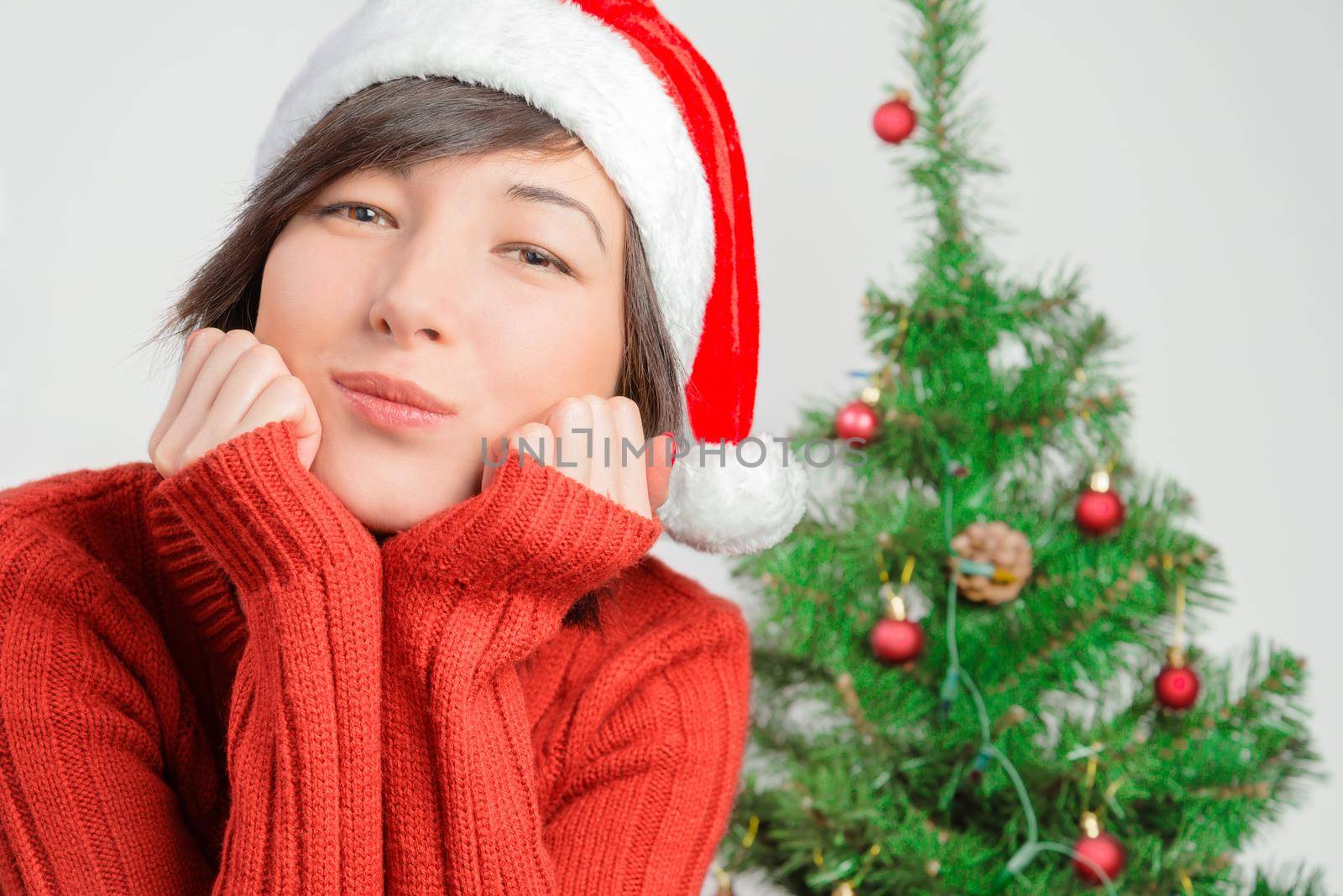 Young woman waiting for a holiday on the background of Christmas tree