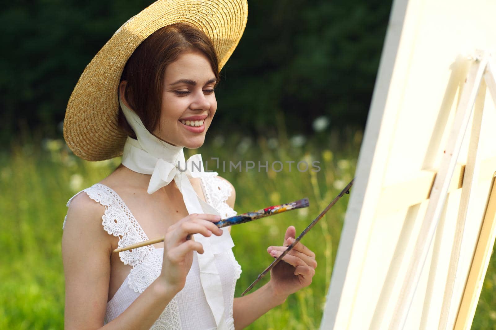 Woman in white dress artist paints on nature palette creative. High quality photo