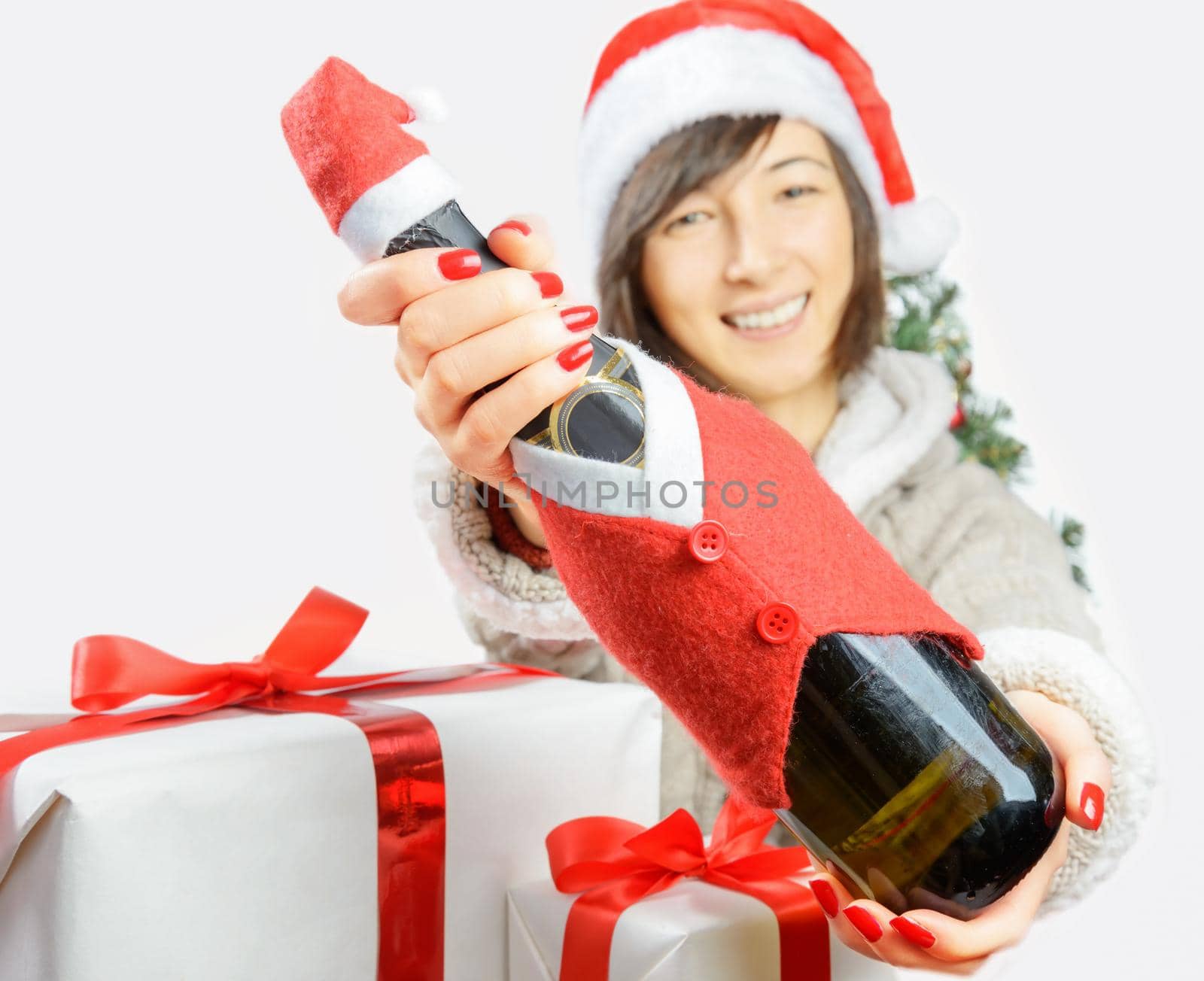 Happy woman in santa hat is giving a bottle of champagne