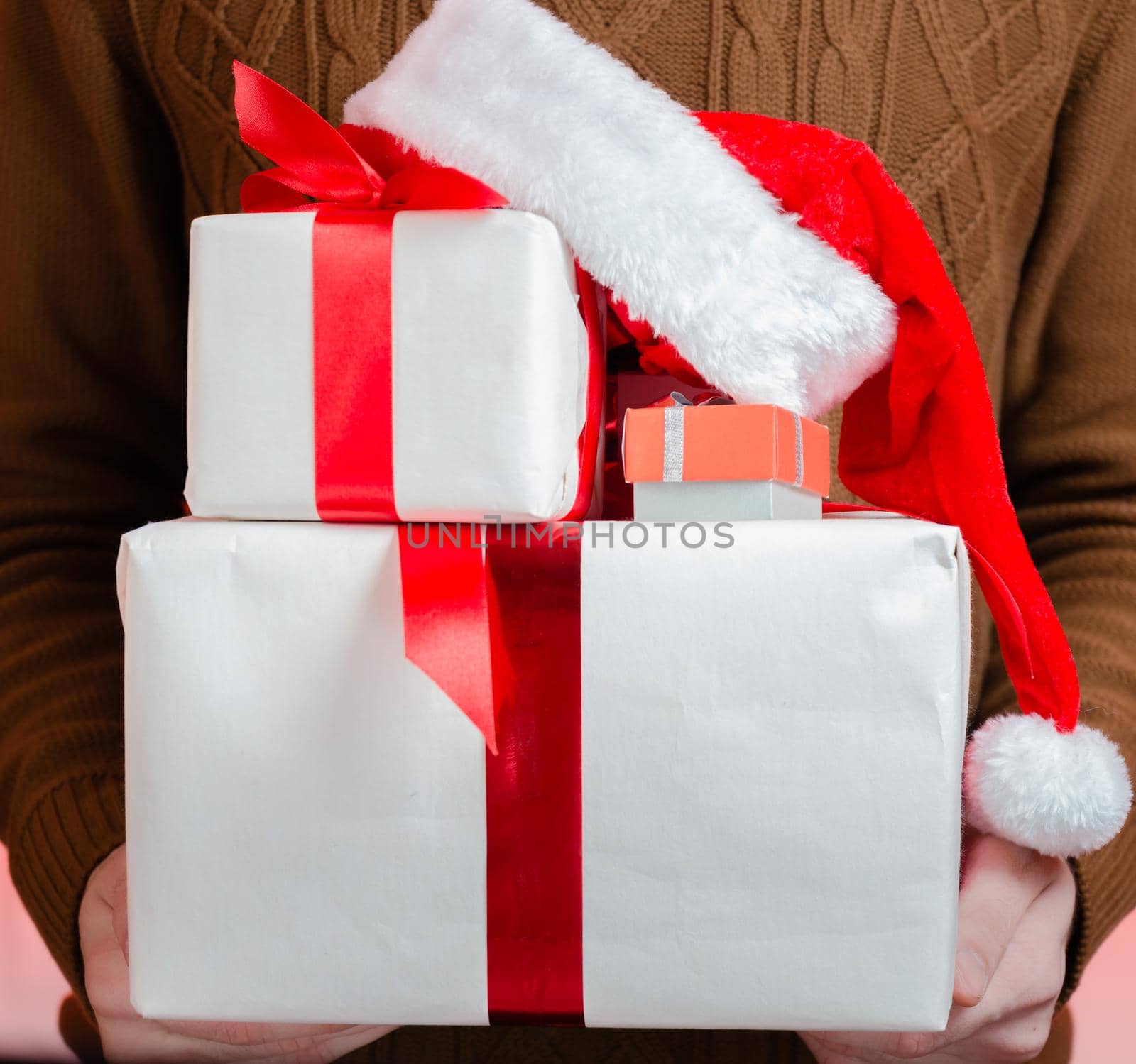 Unrecognizable man holding gift box and santa hat, close-up