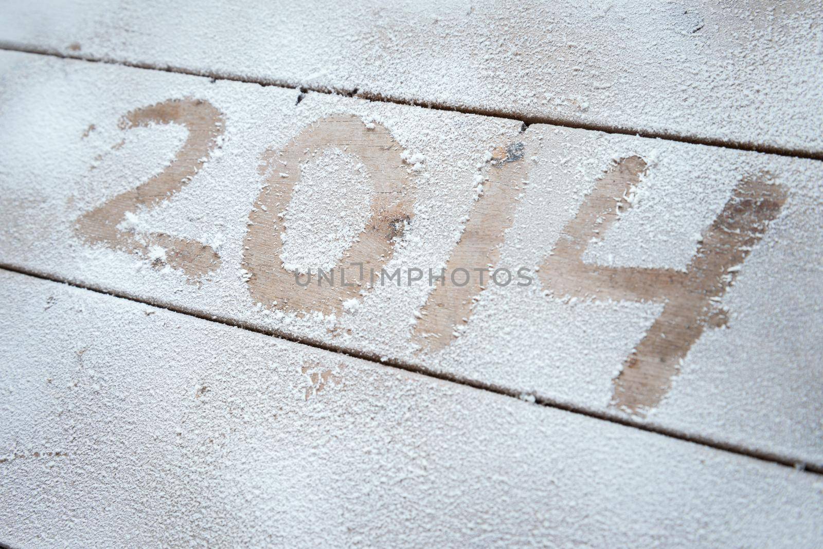 2014 written in snow on a wooden background