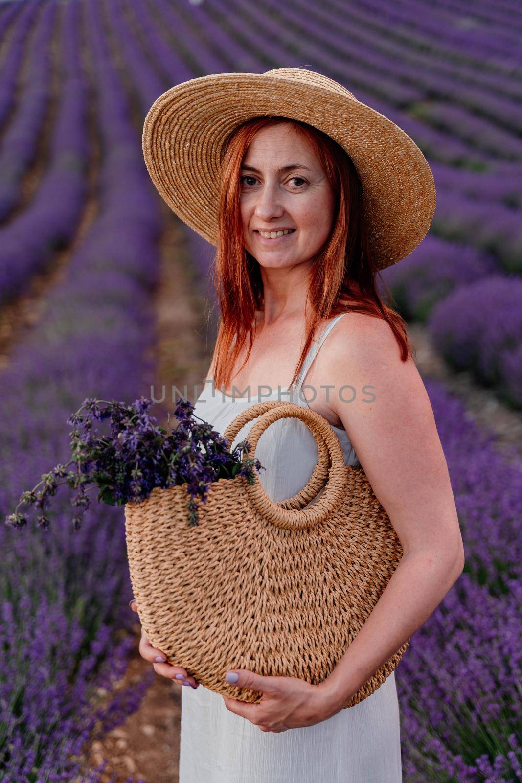 charming Young woman with a hat and white dress in a purple lavender field. LIfestyle outdoors. Back view by Matiunina
