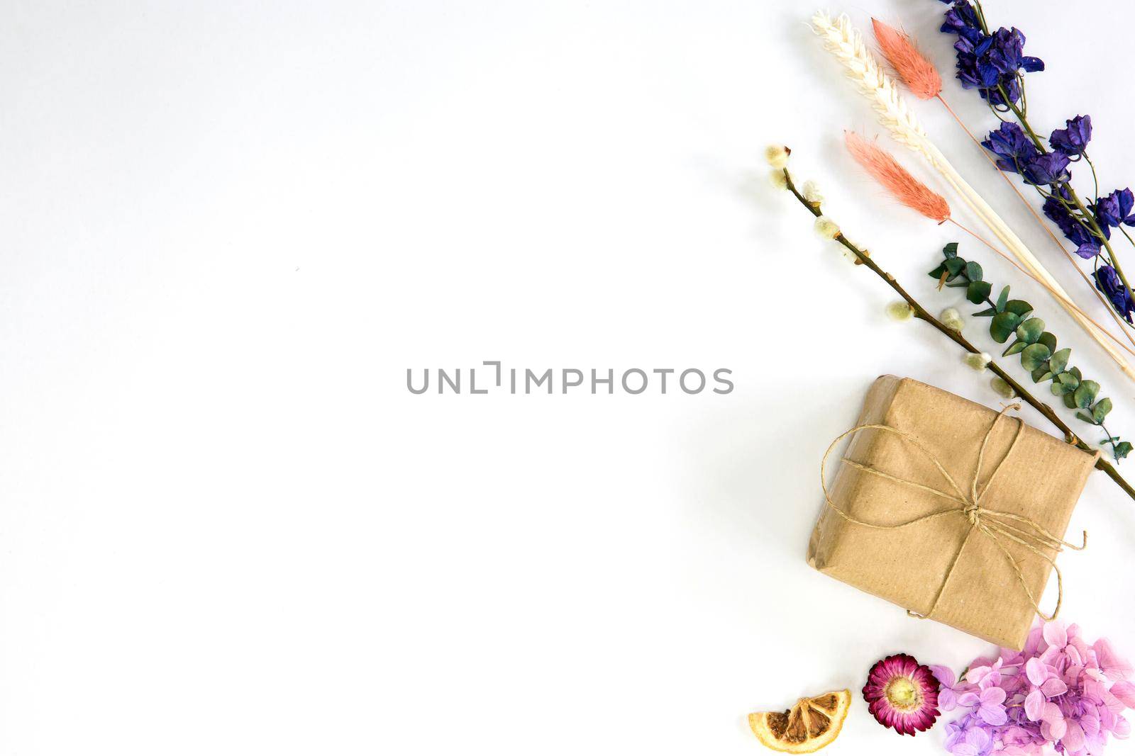 Fresh colorful dried spring flowers and brown craft paper gift box, top view with copy space isolated on white background, bright colors,flat lay,modern design, Mothers Day, Birthday,Valentines Day cheerful
