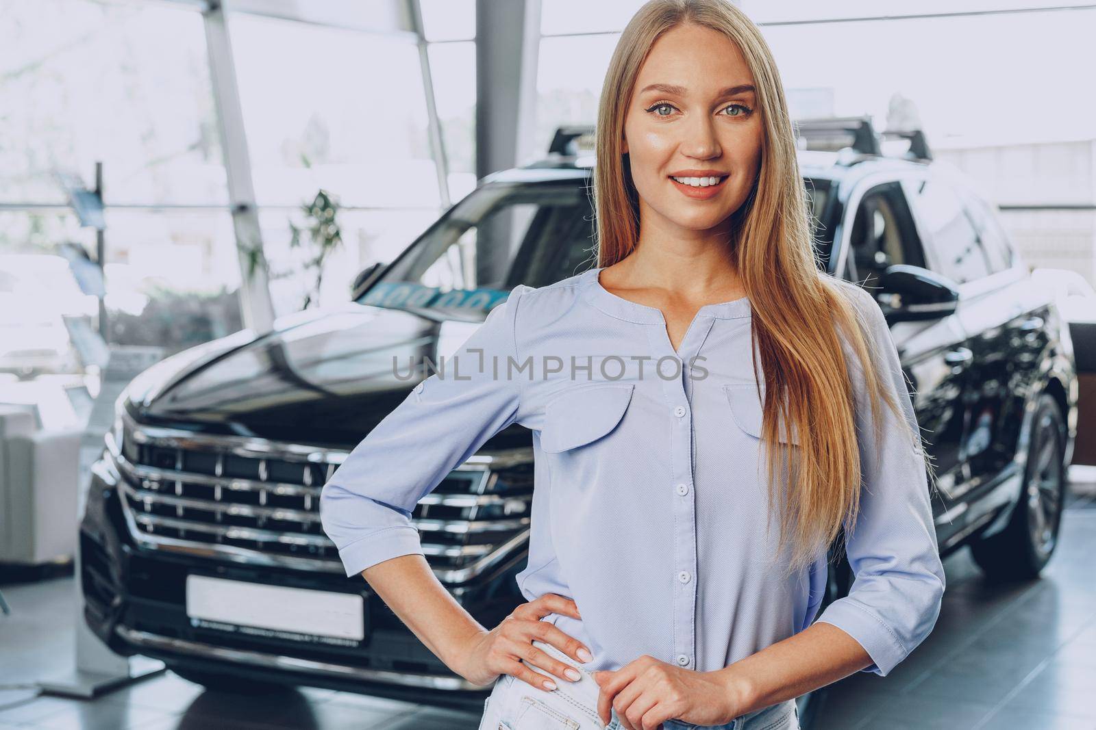 Young woman checking out a new car she is going to buy in car salon
