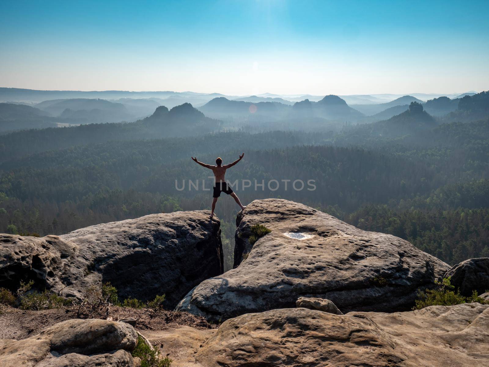 Shirtless male silhouette with raised arms on sharp mountain top. by rdonar2