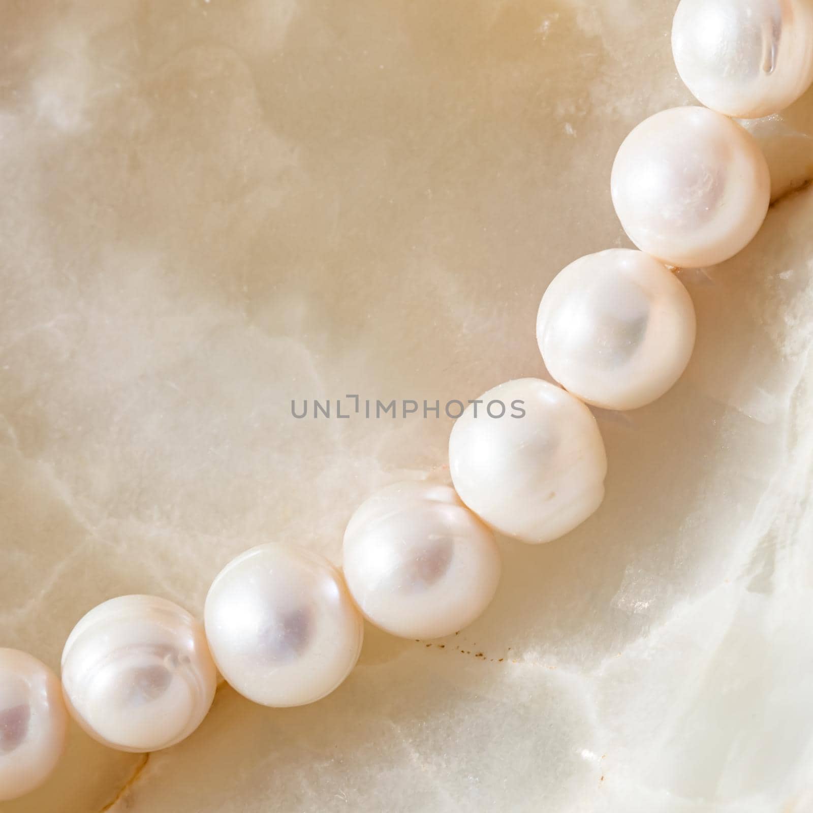 Nature white string of pearls on marble background in soft focus, with highlights by Olayola