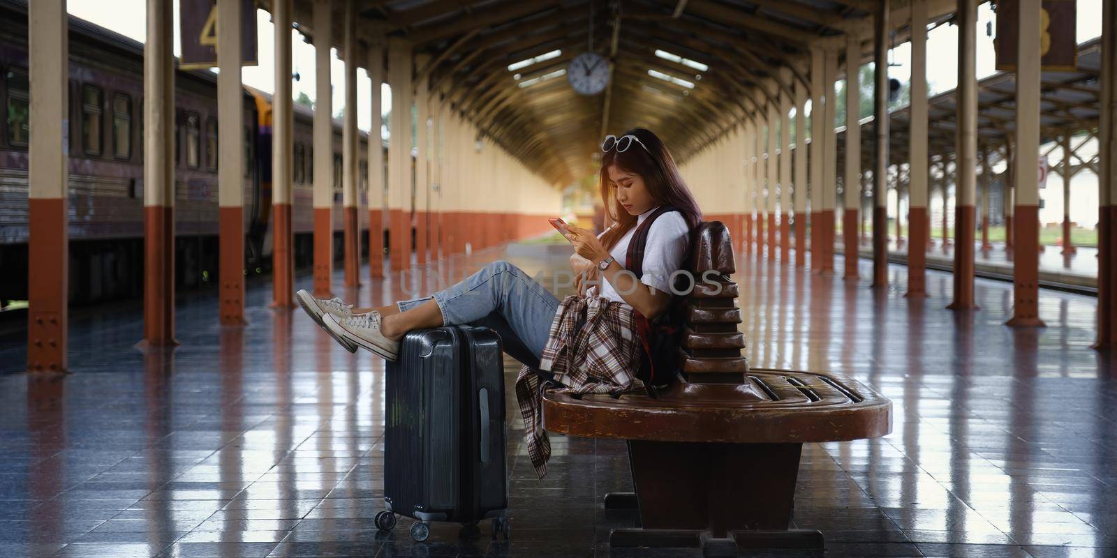 Alone traveler tourist using smartphone with luggage at train station. work and travel lifestyle concept. soft focus.