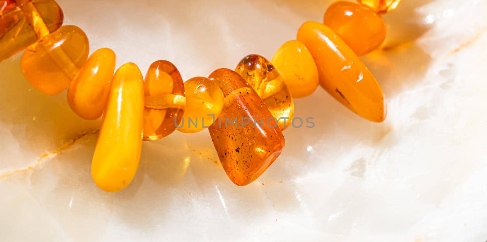 Solar beads of fiery amber on onyx marble background. Natural stone backdrop.