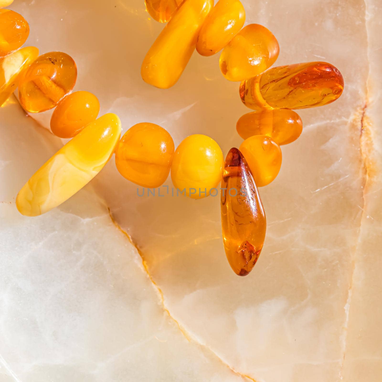 Solar beads of fiery amber on onyx marble background. Natural stone backdrop by Olayola