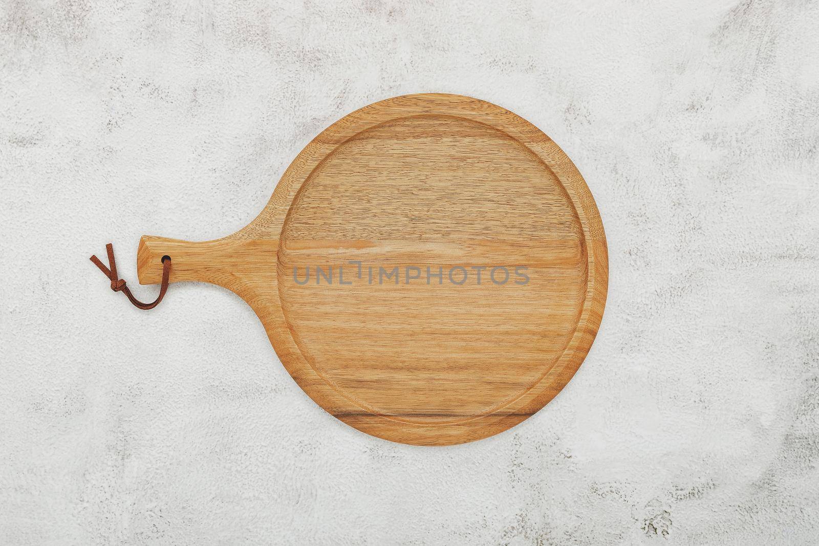 Empty wooden pizza platter set up on white concrete. Pizza tray on white concrete background flat lay and copy space. by kerdkanno