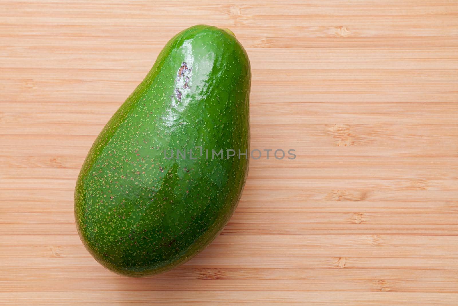 Fresh avocado on wooden background. Organic avocado healthy food concept.
 Avocado on Bamboo cutting board.The avocado is popular in vegetarian cuisine and weight control. by kerdkanno