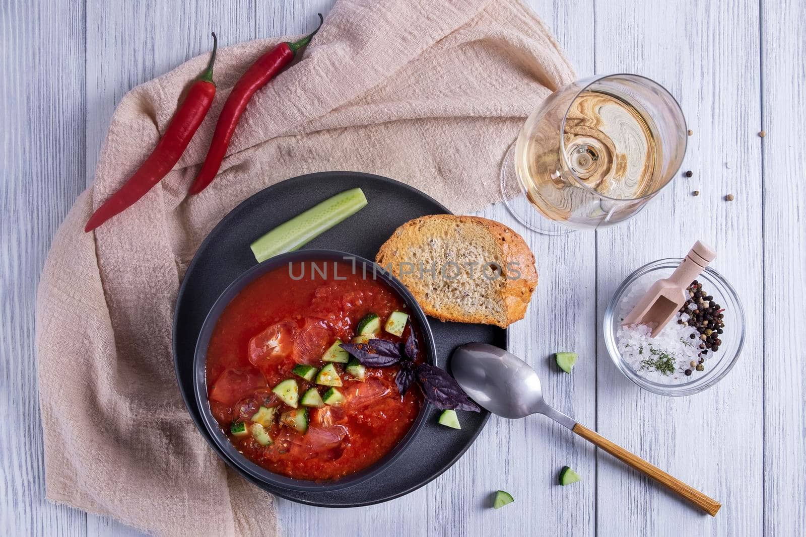 Top view a bowl of Spanish traditional cold tomato and cucumber gazpacho soup and a glass of white wine with cereal bread. Summer food. Healthy and vegetarian food. Selective focus.