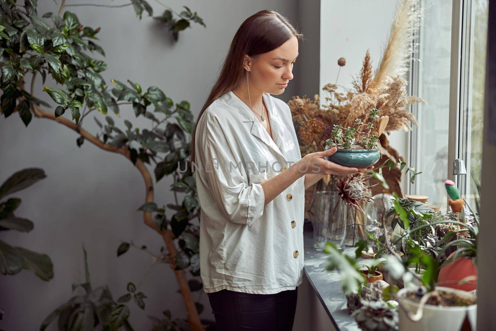 caucasian confident happy florist is working with composition made from glass stones and plants in botanic shop by Yaroslav_astakhov