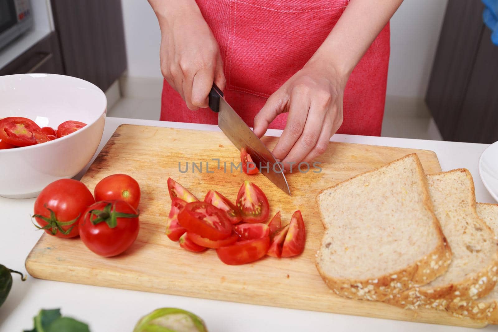 close up of hand cutting tomato on board in kitchen room by geargodz