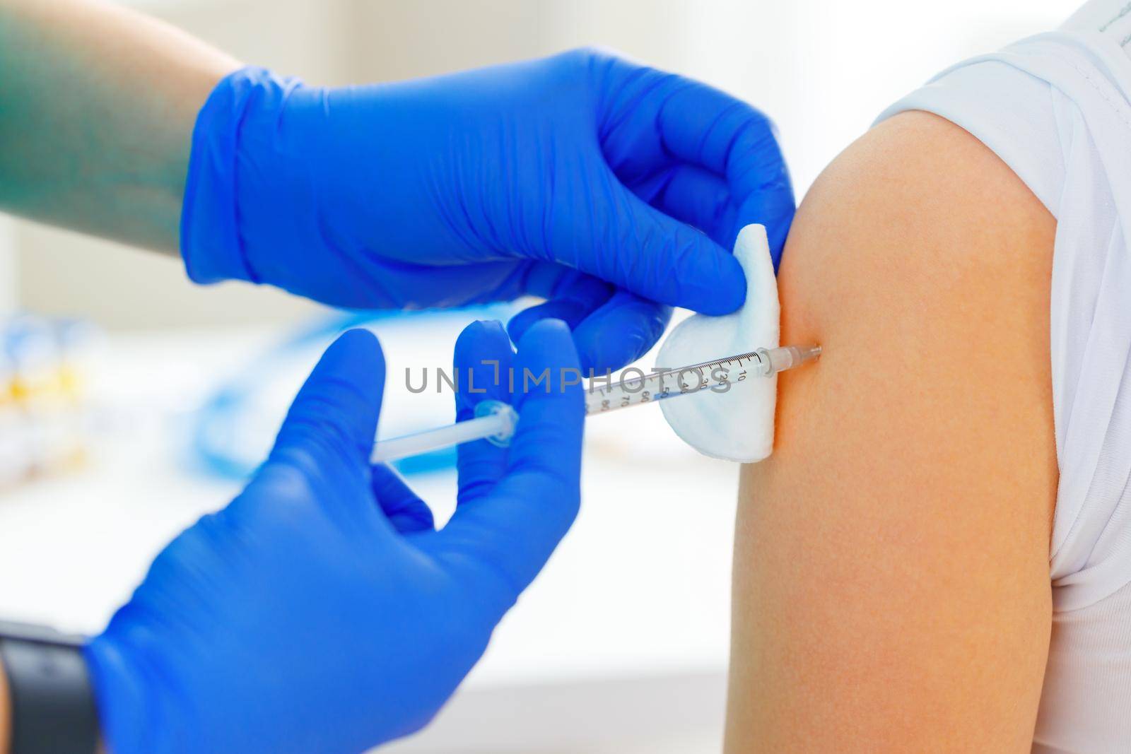 Doctor hands making a vaccination in the shoulder of patient close up