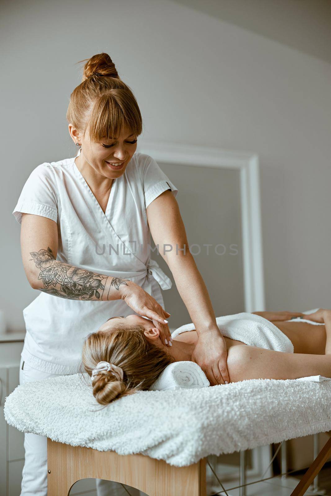 Therapist is doing face relaxing massage to a young woman in modern wellness cabinet