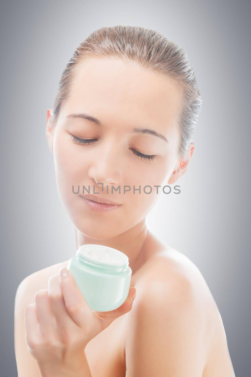 Woman looks at a jar of cream, concept of skincare