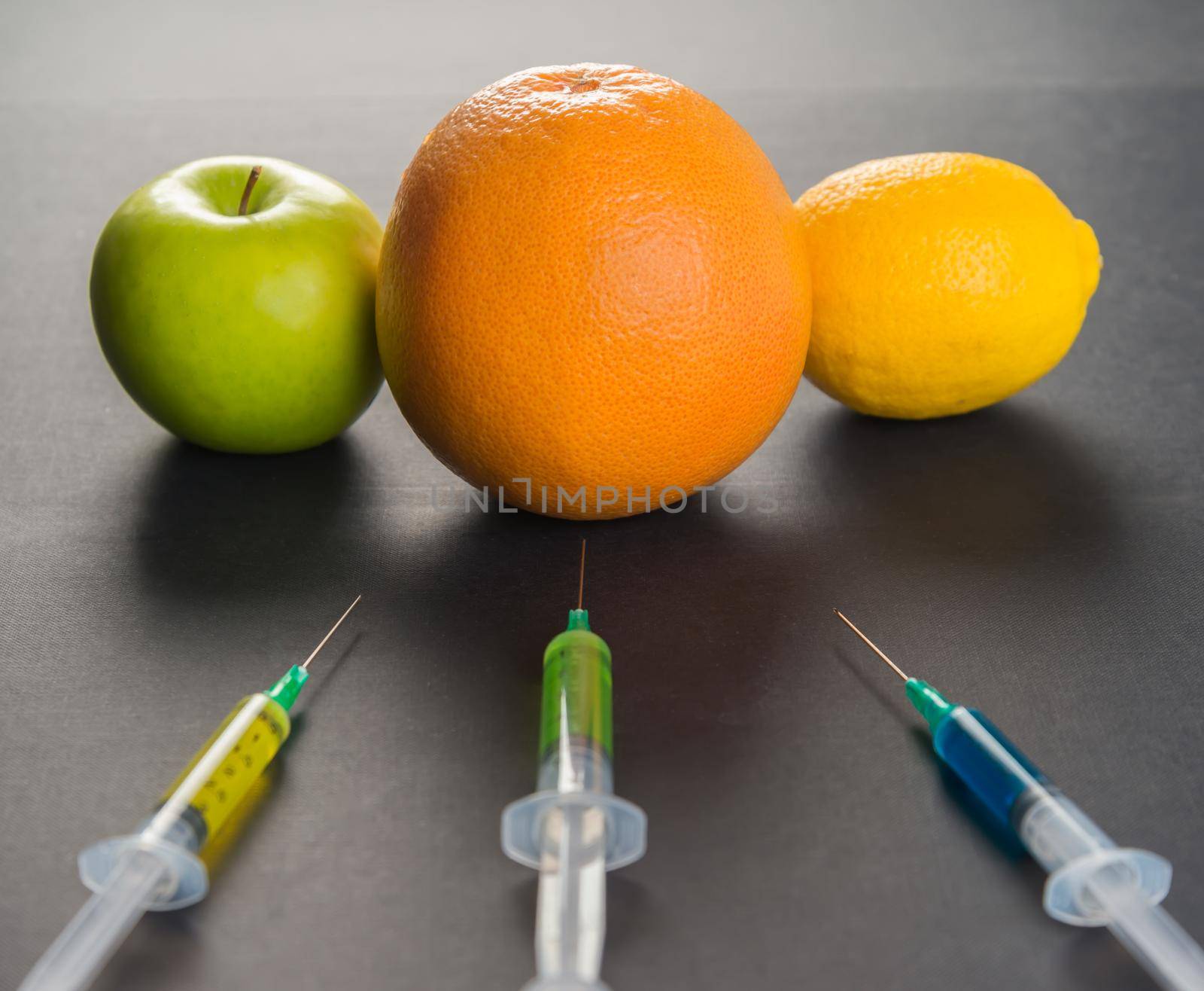 Сhemical liquid in the syringe and fruits on a black background
