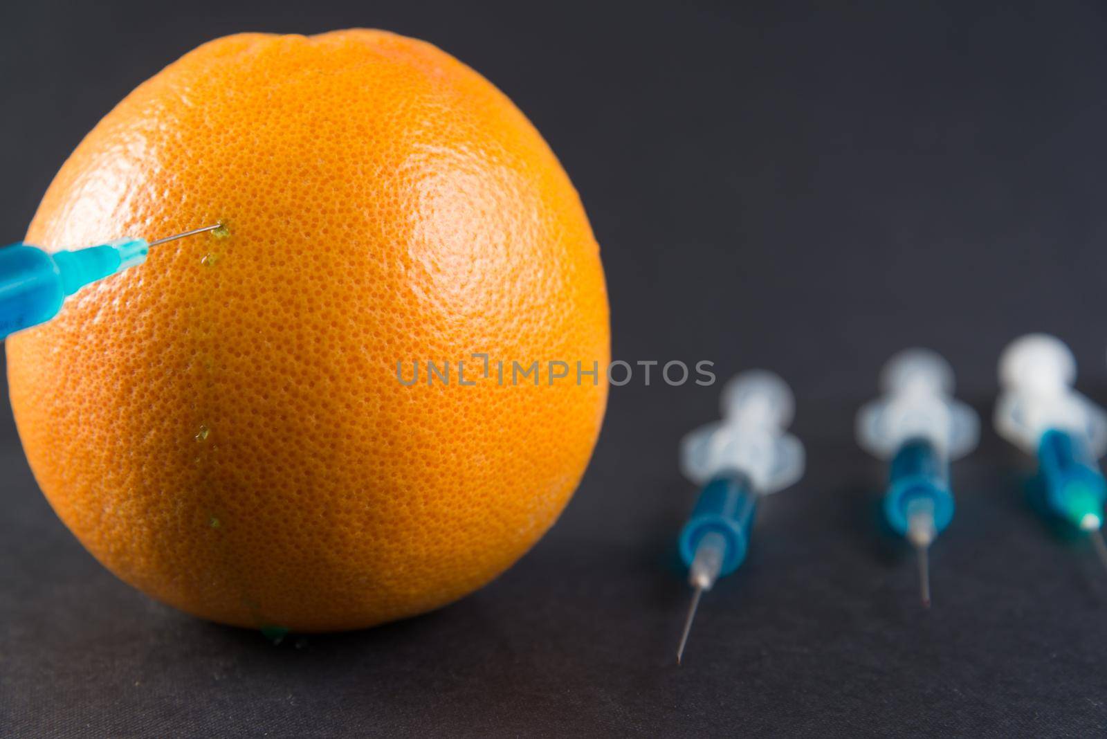 Blue liquid in the syringe injected into grapefruit, top view