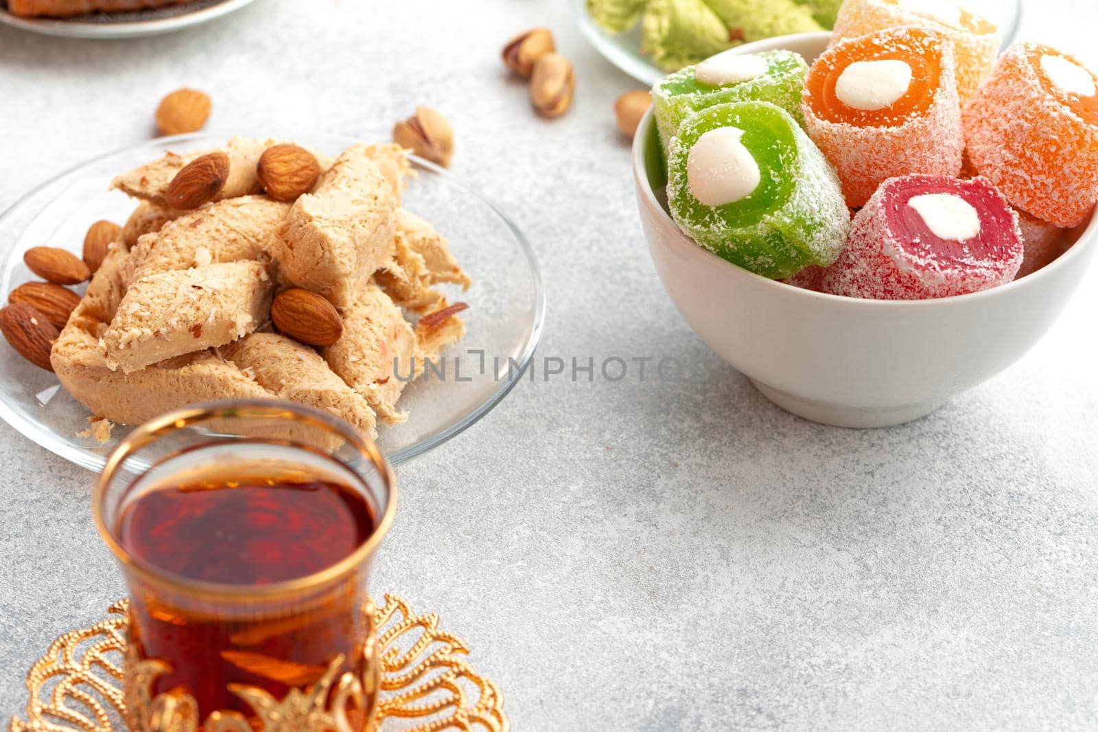 Assortment of Turkish delights with glass of tea on gray background, close up