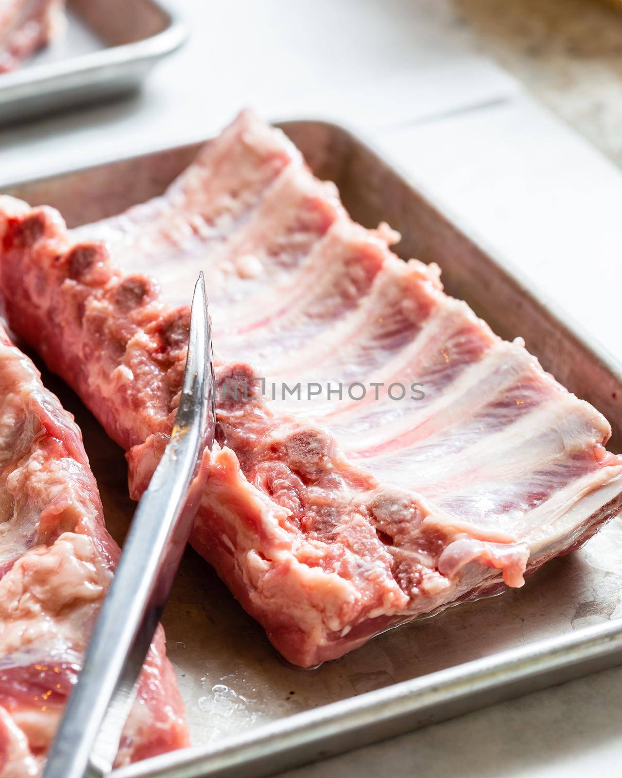 Spare ribs uncooked on stainless steel platter. by Syvanych
