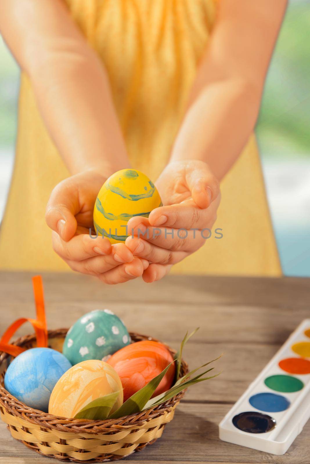 Unrecognizable little girl holds Easter egg indoor
