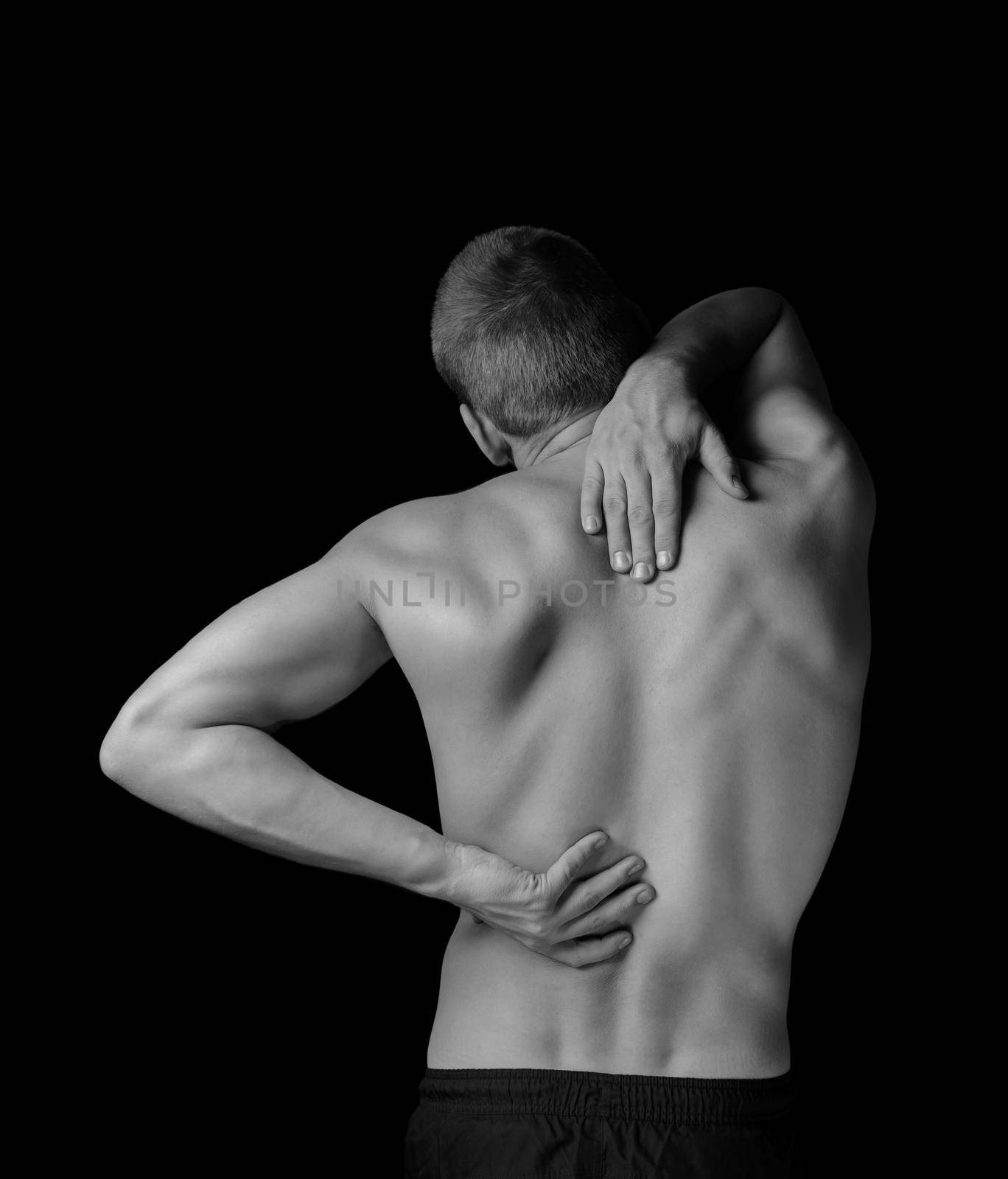 Man is touching the back, concept of pain in the spine, monochrome image